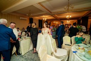 Reception venue with cream-colored table linens and classic chandelier lighting.