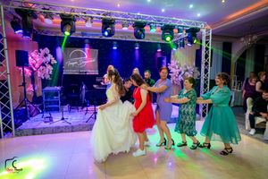 Ballroom dancers fill a spacious venue decorated with professional lighting and sound equipment during an evening event.