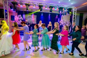 Panoramic view of a formal dance event showing multiple couples dancing under theatrical lighting and stage rigging.