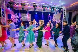 Dance floor panorama showing couples in formal attire dancing under dramatic purple stage lighting.
