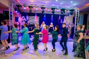 Wide angle view of an elegant ballroom dance event with professional lighting and staging equipment.
