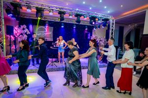 Dance floor filled with couples during a formal event under theatrical lighting and professional staging.