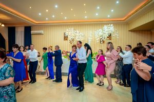 Group dance formation in a brightly lit ballroom with elegant chandeliers and decorative lighting.