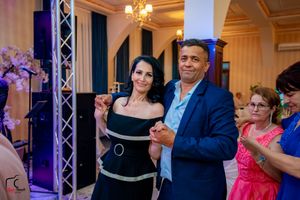 Formal dance celebration with couples dancing under dramatic purple lighting.