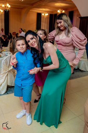 Wedding guests dancing and celebrating in a ballroom with elegant chandeliers and decor.
