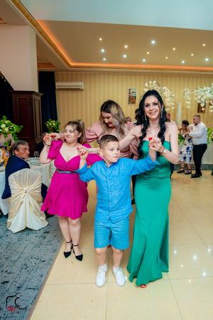 Group dance formation with participants wearing colorful outfits in a bright ballroom setting.