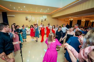 Lively dance party at a wedding reception with guests in bright formal attire.