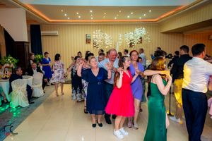Wedding reception dance floor with guests in colorful formal wear under elegant lighting.