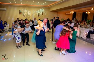 Panoramic view of wedding guests dancing and mingling under crystal chandeliers.