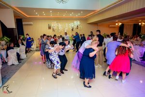 Wedding party dancing in an elegant ballroom with ambient lighting and formal decor.