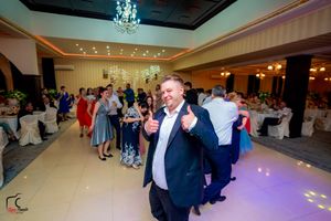 Guests enjoying a lively celebration on the dance floor under elegant chandeliers at an indoor event venue.