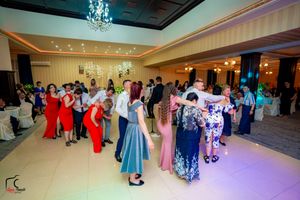 Couples dancing together at an elegant reception with colorful formal attire and crystal chandeliers overhead.