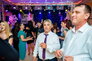 Lively dance party scene with guests celebrating under dramatic purple lighting and starlit backdrop.