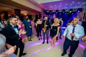 Wedding reception guests dancing and socializing on a colorfully lit dance floor in an elegant ballroom.