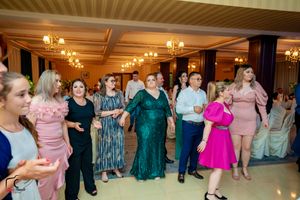Wedding guests dancing and mingling in a banquet hall with warm lighting and striped wallpaper.