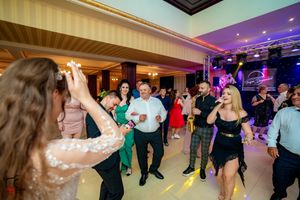Wide angle shot of a wedding reception dance floor with colorful party lighting and chandeliers.
