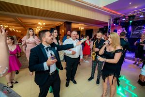 Wedding party dancing in a ballroom with purple mood lighting and elegant decor.