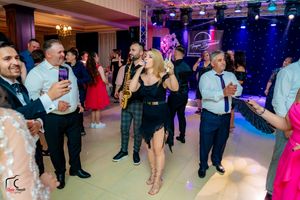 Panoramic view of wedding guests enjoying themselves on a lively dance floor with colorful lighting.
