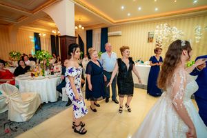 Wedding reception guests dancing in an elegantly decorated ballroom with floral accents.
