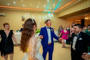 Festive wedding celebration with guests dancing in a beautifully lit ballroom.