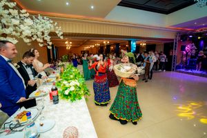 Guests enjoying a lively celebration in an elegantly decorated banquet hall with floral arrangements and mood lighting.