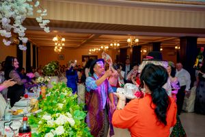 Festive gathering in a reception hall with colorful attire and decorative white flowers.