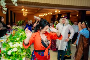 Lively party scene in a banquet hall with elegant floral decorations and ambient lighting.