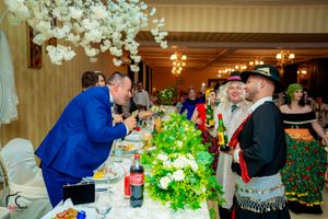 Indoor celebration venue with hanging chandeliers and white floral arrangements.