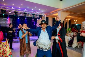Festive ballroom celebration with colorful lighting and people dancing on a spacious dance floor.