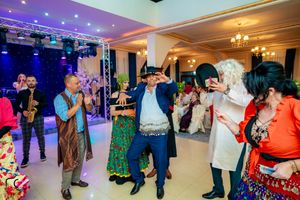 Dance celebration with colorful traditional outfits under purple and blue lighting.