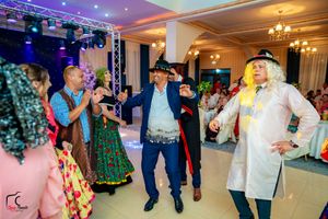 Lively indoor celebration with dancers in traditional costumes under ambient lighting.