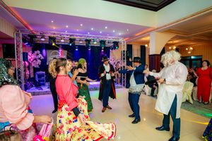 Large ballroom event space with purple uplighting and guests dancing during a celebration.
