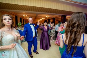 Wedding celebration in a grand ballroom with guests in formal attire dancing and socializing.