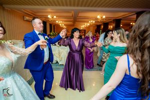 Formal event in an elegant ballroom with guests in colorful dresses dancing and celebrating.
