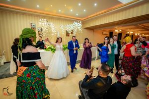 Wedding reception dance party in a ballroom with colorful dresses and festive lighting.