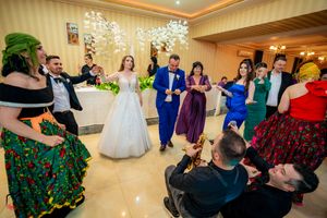 Large group dancing and celebrating at an elegant indoor wedding reception venue.