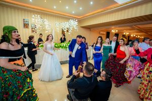 Wedding guests dancing in a ballroom decorated with chandeliers and striped wallpaper.