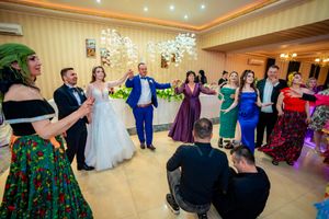 Lively wedding celebration with guests dancing in formal attire at an indoor venue.