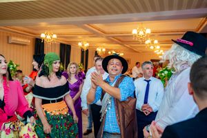Festive ballroom celebration with dancers in formal attire under warm chandelier lighting.
