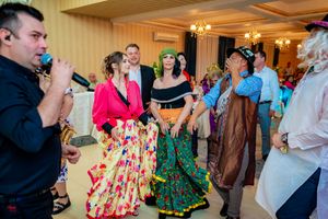 Energetic dance party scene in a well-lit ballroom with guests in colorful formal wear.