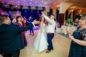 Panoramic view of an active dance floor with party guests under purple ambient lighting.
