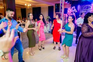 Wedding guests dancing together on a festively lit dance floor with colorful lighting and decor.