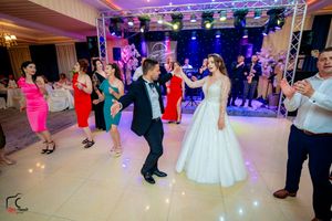Wedding celebration in full swing with guests dancing under professional lighting in an elegant venue.