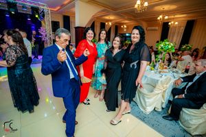 Wedding guests dancing and socializing at a reception with colorful lighting and elegant decor.
