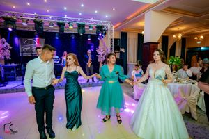 Elegant wedding reception with guests dancing under professional lighting in a decorated ballroom.