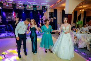 Wedding party dancing together on the dance floor with purple stage lighting and elegant reception decor.