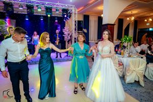 Group dancing together at wedding reception with vibrant lighting and formal attire.