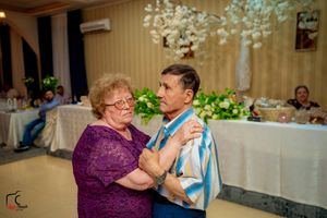 Couple dancing together at wedding reception with white floral decorations in background.