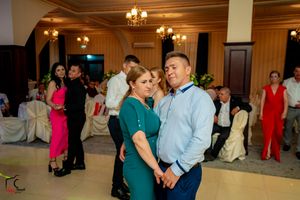 Couple dancing intimately at wedding reception with guests in background.