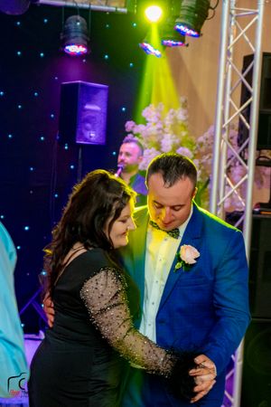 Couple sharing an intimate dance under dramatic stage lighting at wedding reception.